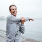 Man stretching outside by harbor