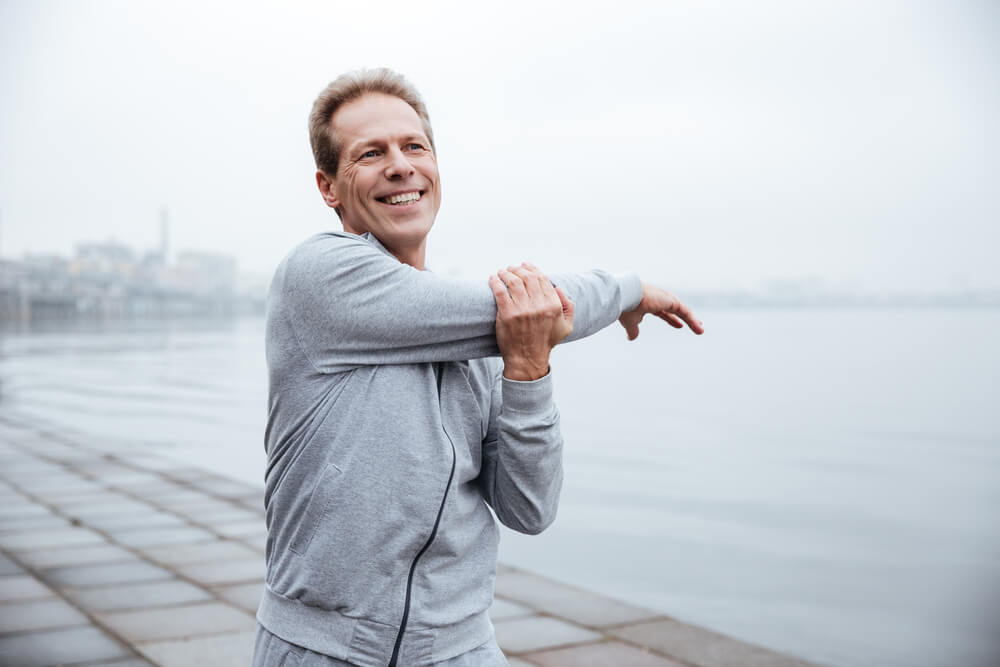 Man stretching outside by harbor