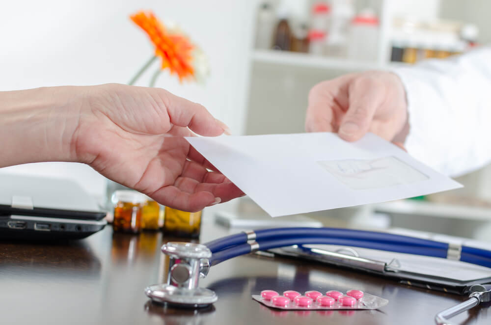 Doctor giving a prescription to his patient in medical office