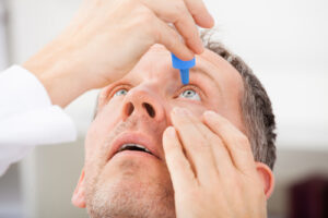 man applying eye drops