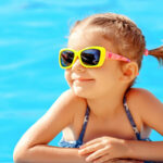 Young girl in a pool with sunglasses on